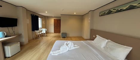 Una habitación de hotel con cama, escritorio, silla, televisión y un cuadro en la pared.