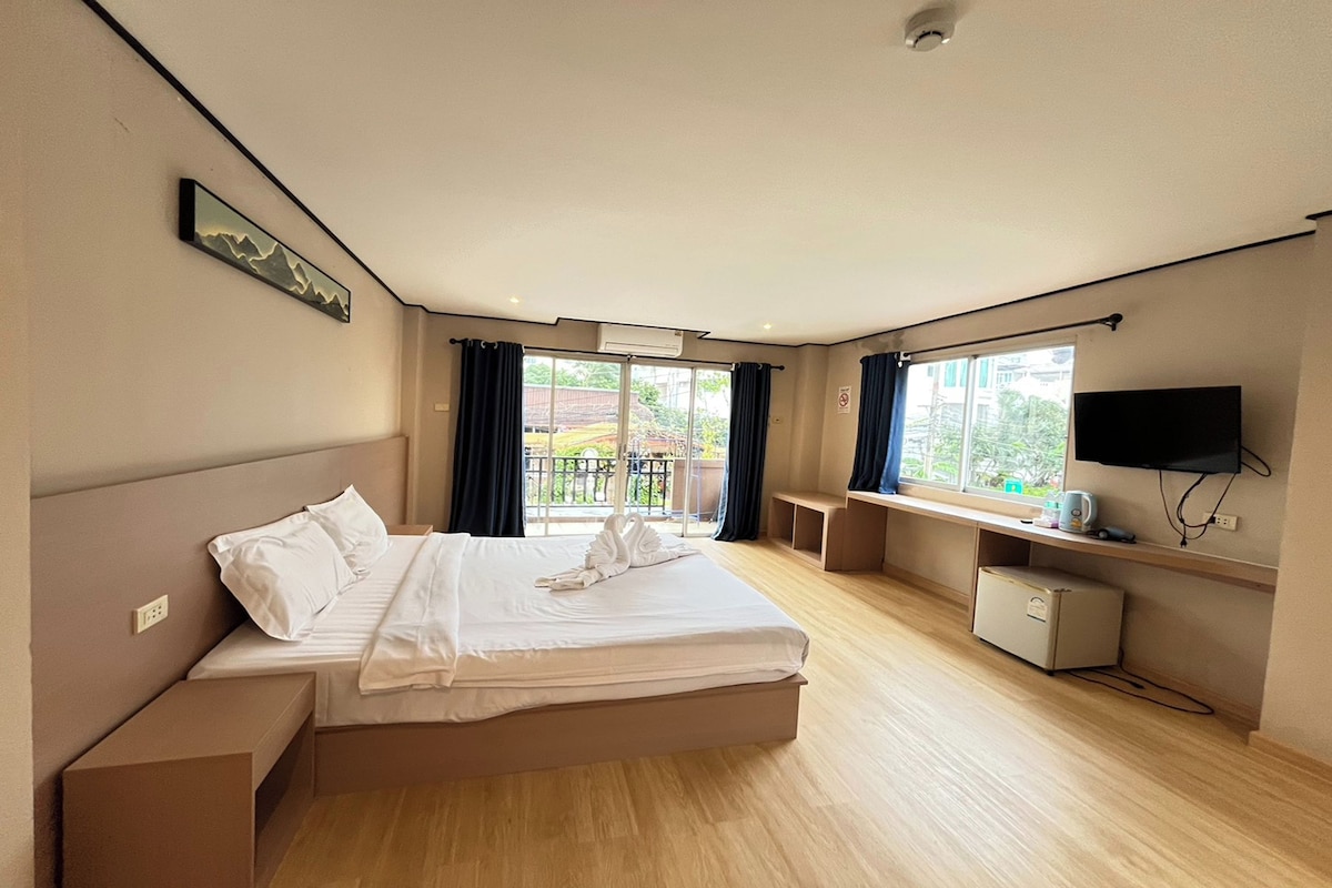A hotel room with a bed, a desk, a television, and a window with a view of the outside.