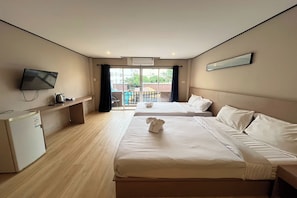 A hotel room with two beds, a TV, a desk, and a view of the outside. - Cocoon Hideaway (Pattaya)