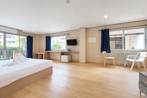 A hotel room with a bed, desk, chair, and a small table. - Cocoon Hideaway (Pattaya)