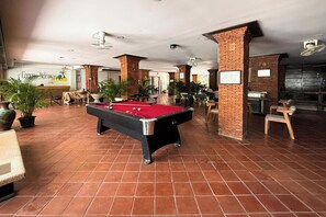 A pool table in a spacious indoor area with brick pillars and potted plants. - Cocoon Hideaway (Pattaya)