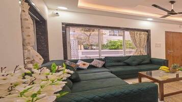 Una sala de estar moderna con un sofá seccional, una mesa de centro y un ventanal con cortinas.