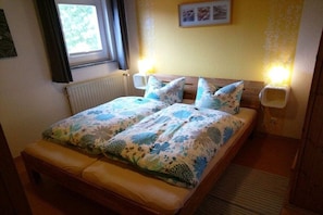 Une chambre à coucher avec un lit, deux lampes de chevet, une fenêtre et un radiateur.