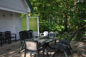Un espace extérieur aménagé avec une table ronde et des chaises, entouré d’arbres et bordé d’un bâtiment doté d’un toit végétalisé.
