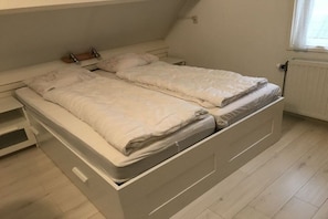 A bedroom with a bed, a nightstand, and a window. - Holiday apartment with 3 bedrooms (Zoutelande)