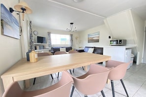 A modern kitchen with a dining area, including a wooden table and pink chairs. - Holiday apartment with 3 bedrooms (Zoutelande)