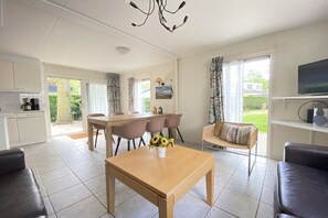 A modern living room with a dining area, a sofa, a coffee table, and a television. - Holiday apartment with 3 bedrooms (Zoutelande)