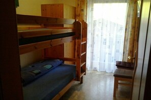 A bunk bed room with a wooden ladder, a single bed with a blue mattress, and a chair. - Holiday apartment with 3 bedrooms (Auffach)