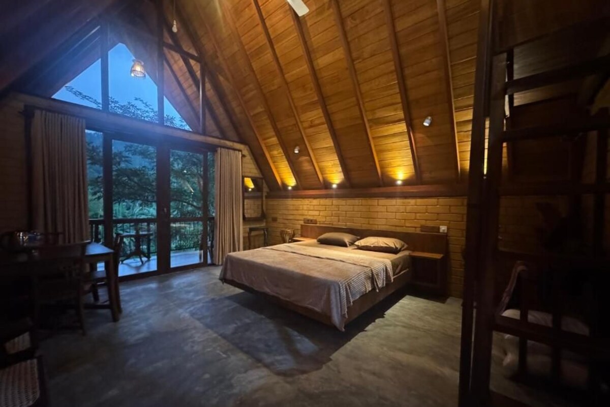 Una camera da letto con un letto grande, un soffitto in legno e vista attraverso una porta vetrata.