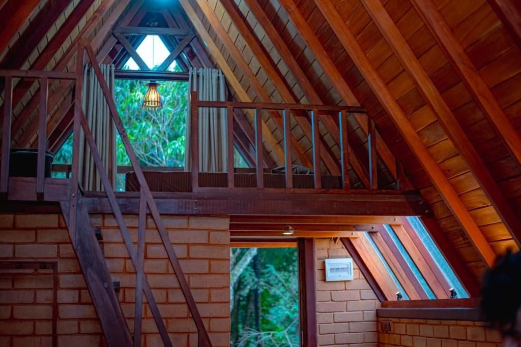 Un dormitorio en el ático con una escalera de madera, un tragaluz y vistas al verdor exterior.