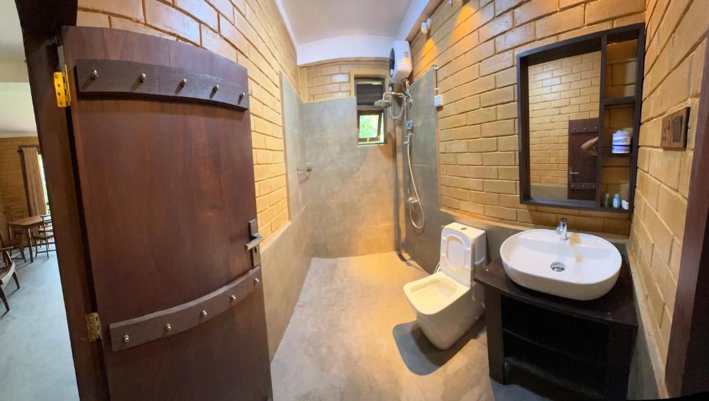 Un bagno con una porta in legno, un lavandino bianco e uno specchio.