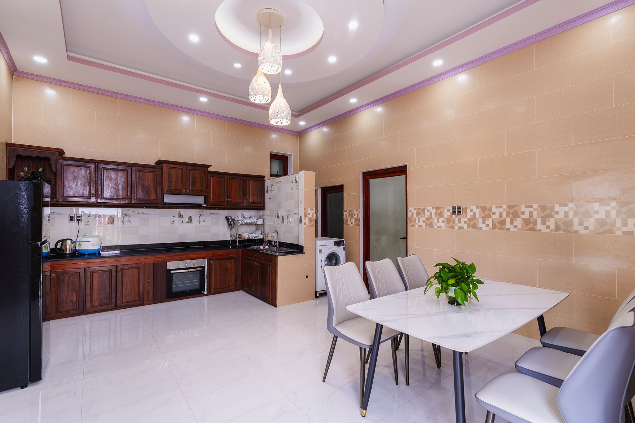A modern kitchen with dark wooden cabinets, a built-in oven, and a dining area with a white table and chairs.