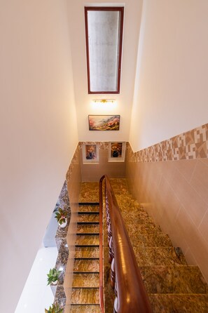 A staircase with a wooden handrail, marble steps, and a wall-mounted picture frame. - Sunlit Seaside Villa Phú Quốc (Phú Quốc)