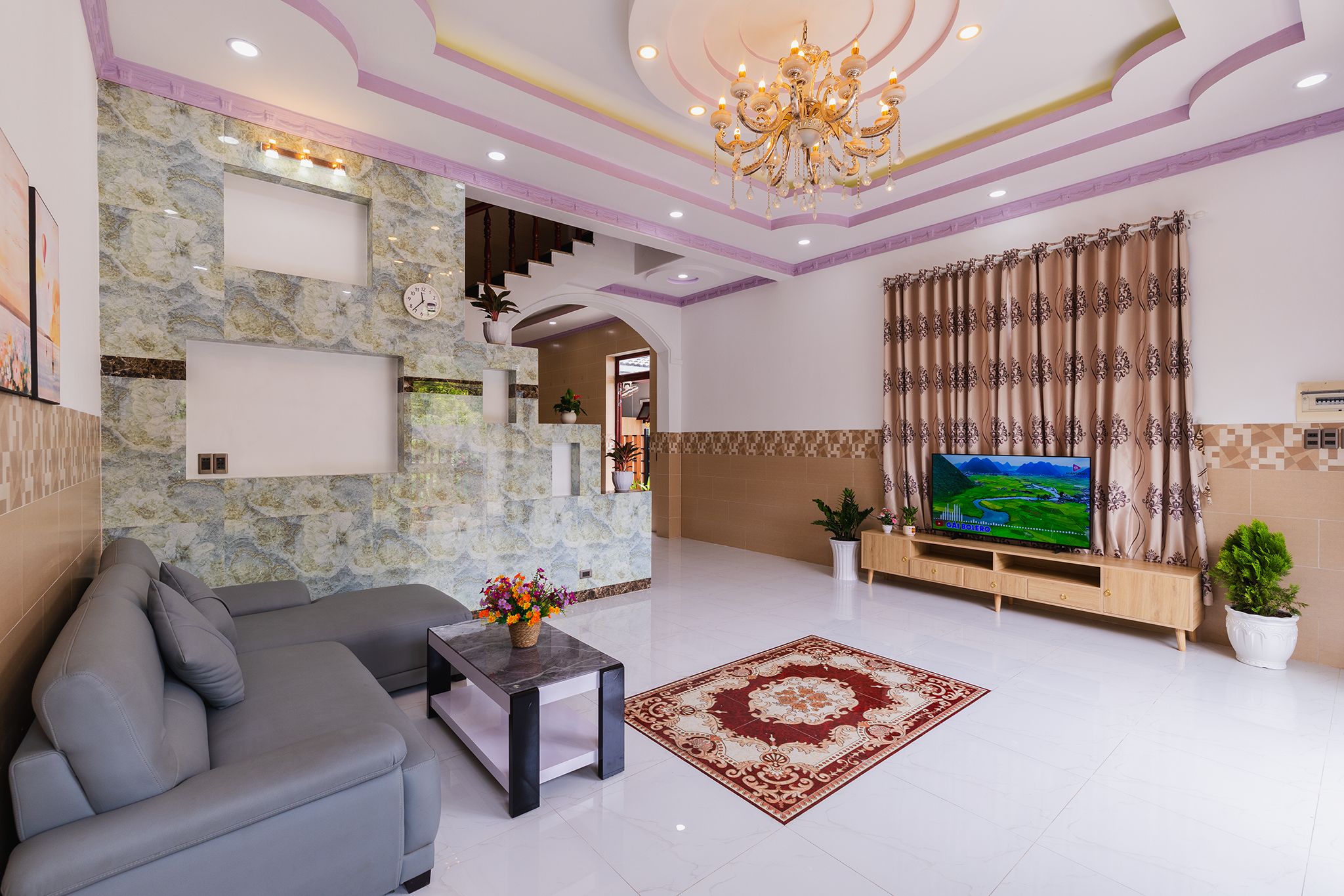 A modern living room with a grey sofa, a coffee table, a TV, and a decorative rug.