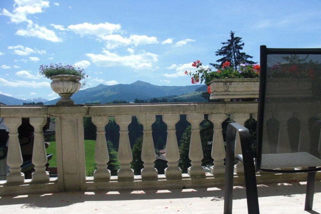 A balcony with a view of mountains, a chair, and a potted plant.