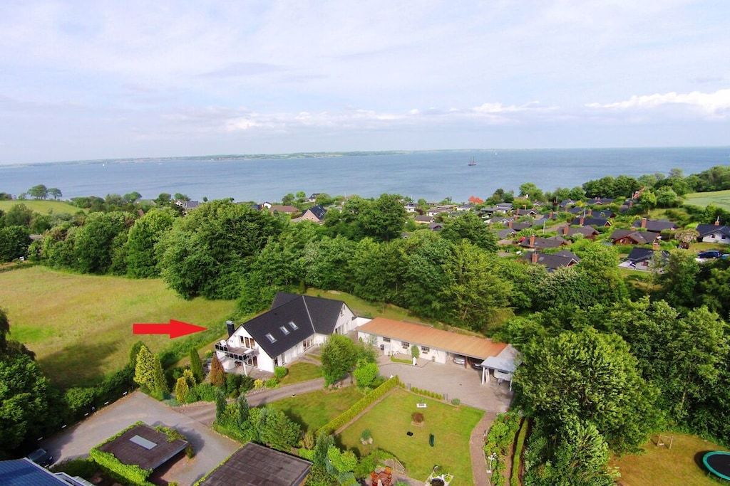 A residential area with houses, a large body of water, and a prominent house with a pointed roof.
