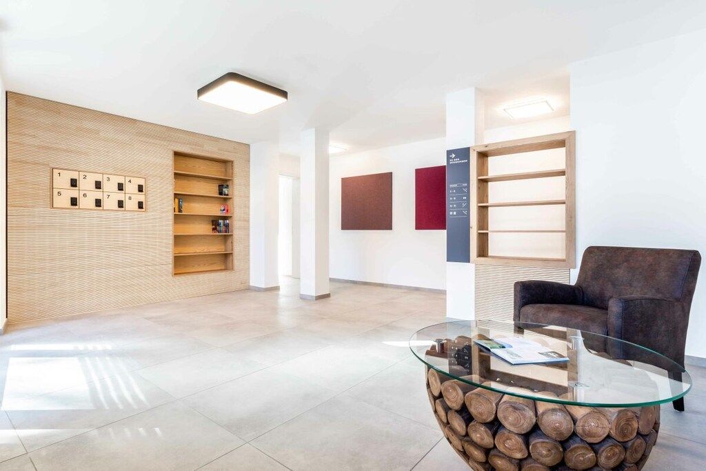 A modern interior with a glass coffee table, wooden shelving, and a brown leather sofa.