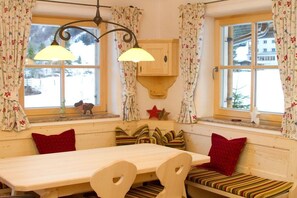 A cozy room with a wooden bench, a table, and two windows with floral curtains. - & Alpine hut "Zum Staubbachfall" (Unken)