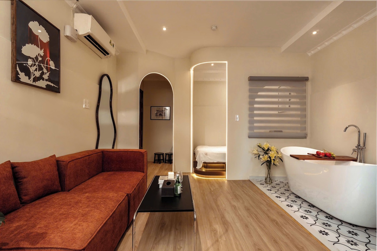 Une chambre d’hôtel moderne avec un canapé, une baignoire et un plancher en bois.