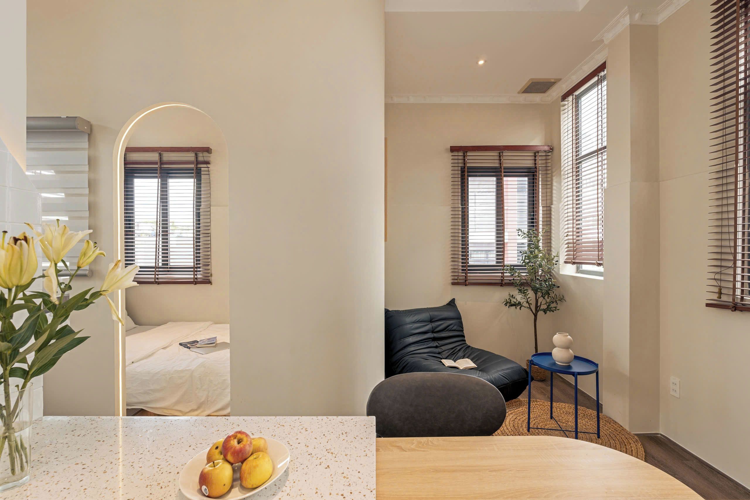 Una habitación moderna con una cama, un sofá, una mesita con un jarrón y una planta.