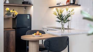 A modern kitchen with a built-in stove, a black refrigerator, and a dining area with a table and chairs.