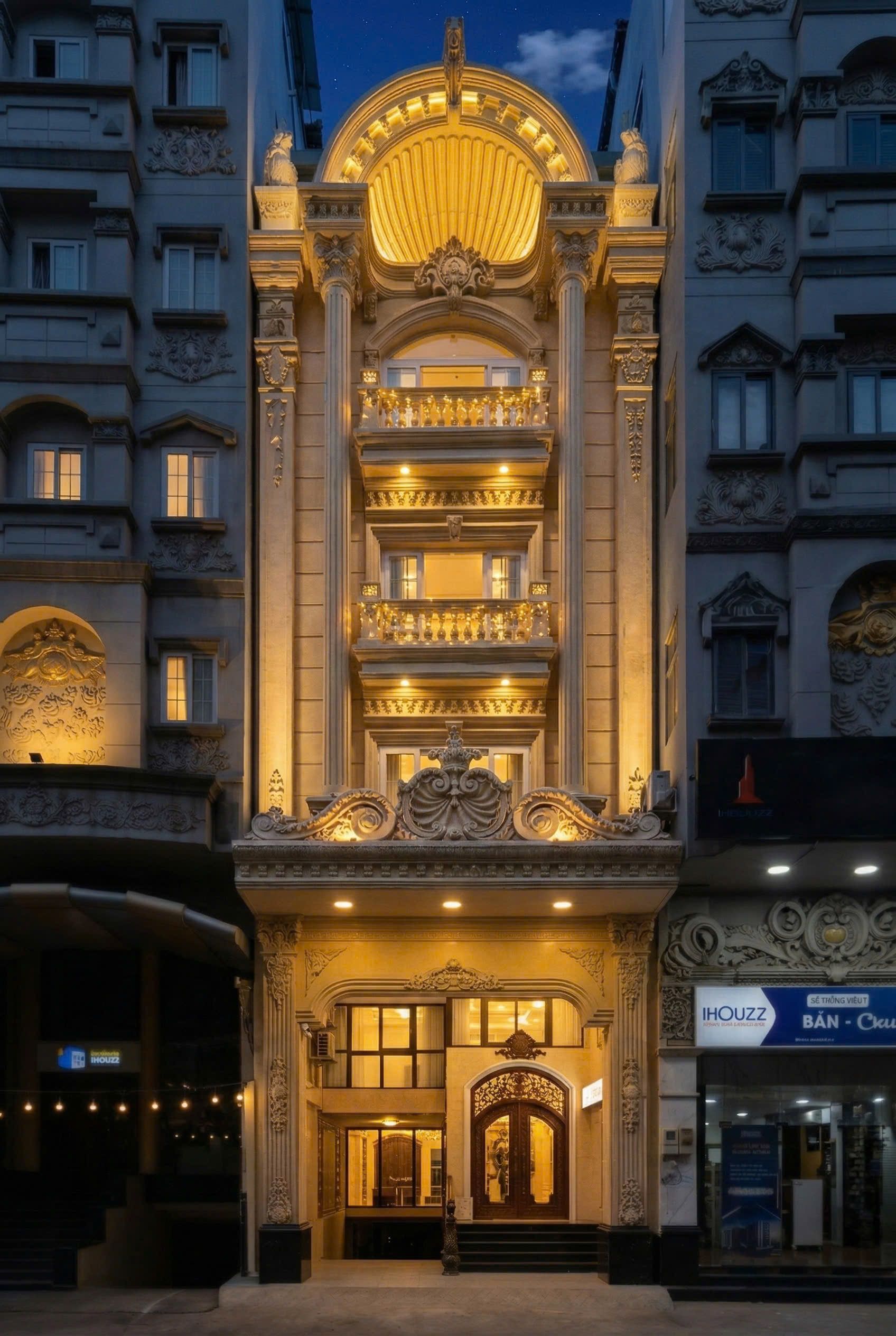 Een statig hotel met een brede bogenpoort, meerdere balkons en decoratieve versieringen.