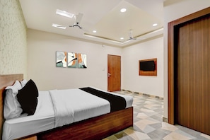 Een slaapkamer met een bed, twee plafondventilatoren, een deur en een aan de muur bevestigde televisie.