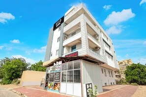Un hotel de diversos pisos amb un cartell destacat de 'HOTEL SHIVALIKA' i un aparador ben visible per a 'HILLMART'.