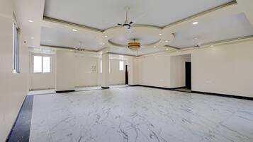 A spacious room with a marble floor, a chandelier, and ceiling fans.