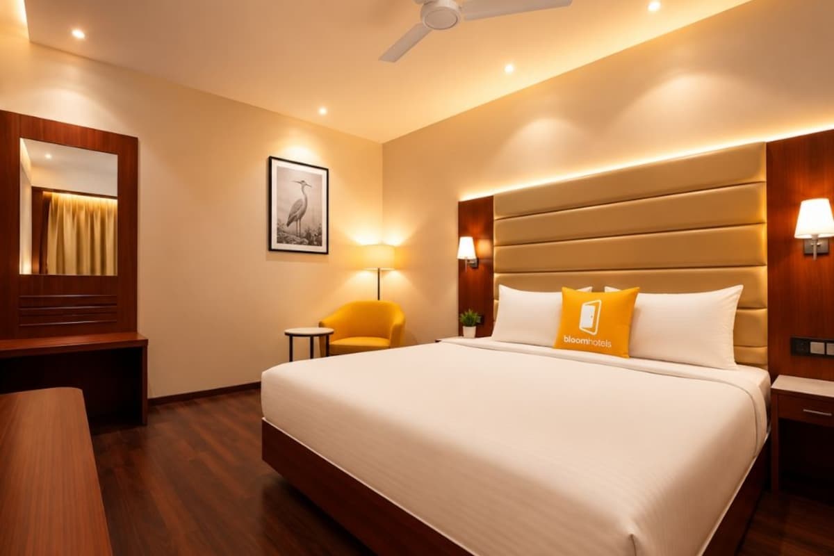 Una habitación de hotel con una cama grande, lámparas de noche, un ventilador de techo y un escritorio de madera.