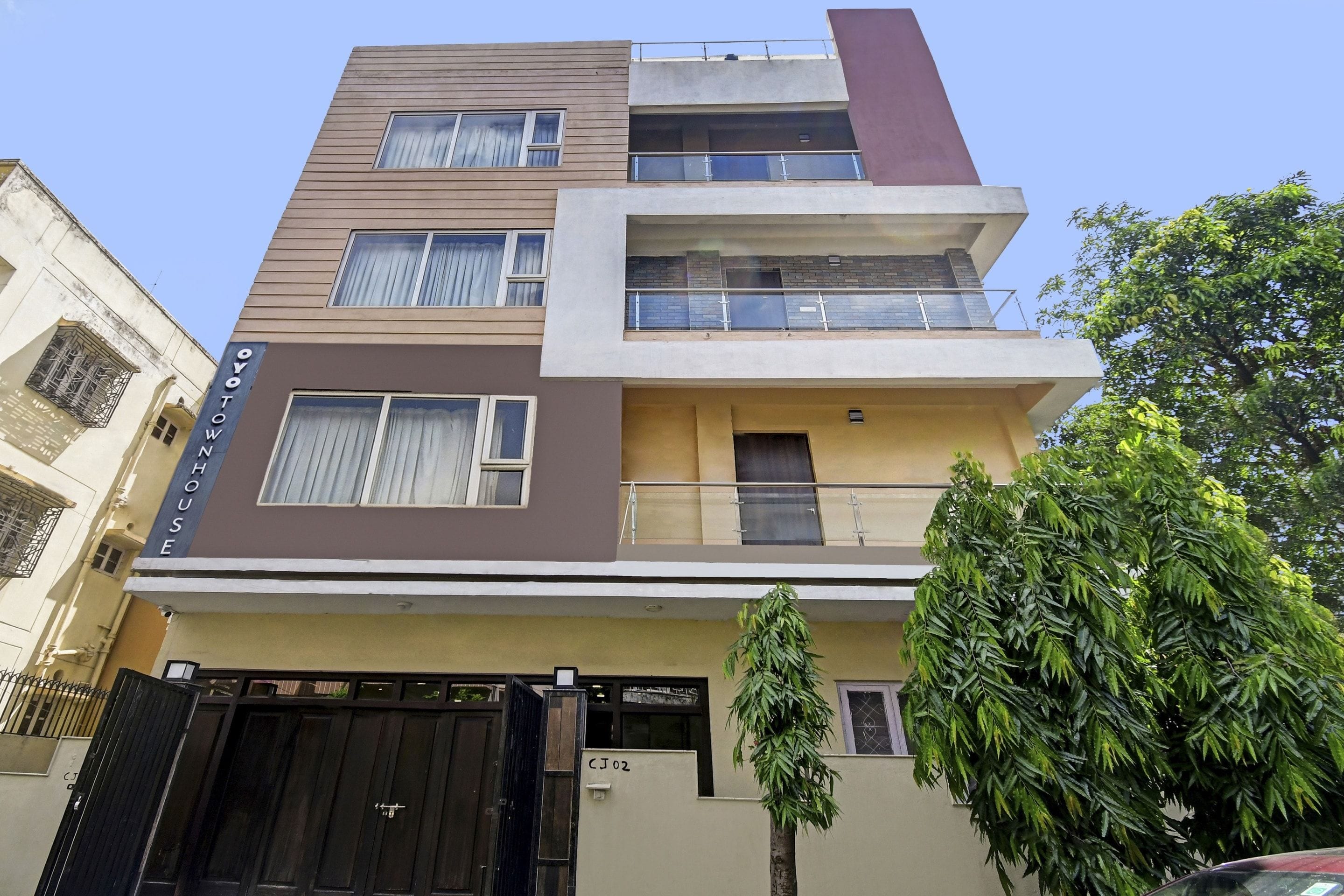 Un edificio residencial de varios pisos con techo plano, varios balcones y una entrada protegida por una reja.