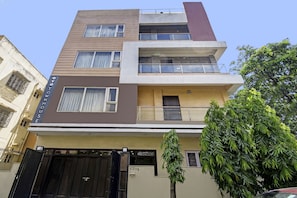 Un edificio residencial de varios pisos con techo plano, varios balcones y una entrada protegida por una reja.