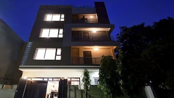 A multi-story residential building with a gated entrance, multiple windows, and a visible balcony.