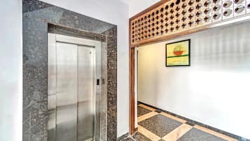 An elevator with a metallic finish and a wall with a geometric patterned design.