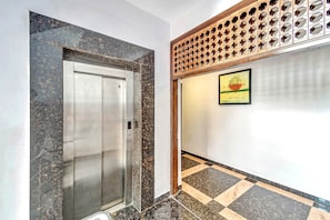Un ascensor con acabado metálico y una pared con diseño geométrico.