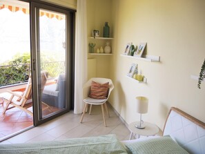 Une chambre avec un lit, une chaise, une petite table et un balcon équipé d’une chaise et d’une table.
