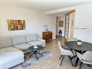 A modern living room with a sofa, coffee table, and dining area with chairs. - Arabella by Interhome (Locarno)