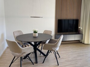 A modern living room with a round table, six chairs, a flat-screen TV, and a fireplace. - Arabella by Interhome (Locarno)