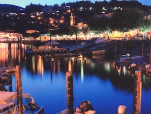 A waterfront marina at dusk with docked boats and a calm water surface reflecting the lights. - Residenza Lido Golf by Interhome (Ascona)