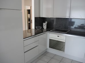 Eine Küche mit Backofen, Kaffeemaschine und einer Schüssel auf der Arbeitsfläche.