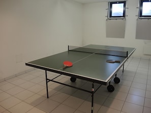 A ping pong table with a red paddle in the foreground and a table tennis paddle in the background. - Residenza Lido Golf by Interhome (Ascona)