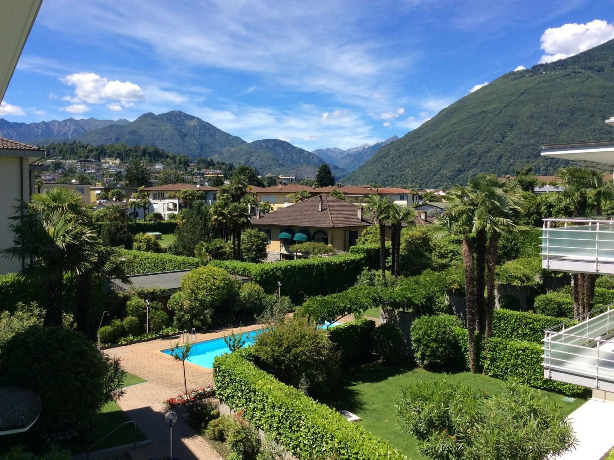 A residential area with a swimming pool surrounded by lush greenery and a mountain backdrop.