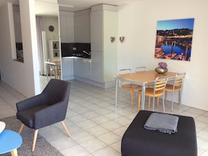 Ein modernes Wohnzimmer mit einer Couch, einem Esstisch mit Stühlen und einer Küche im Hintergrund.