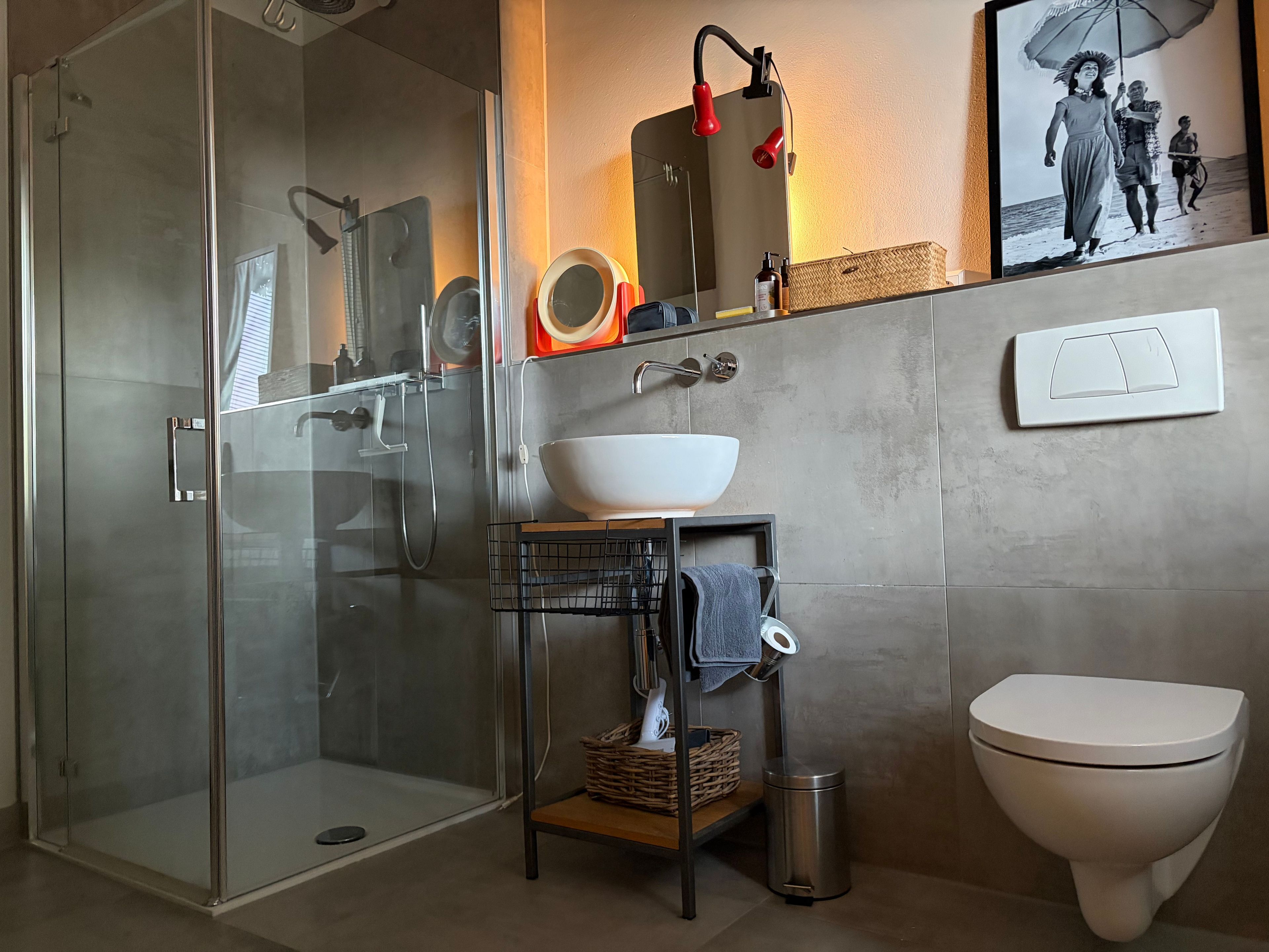 Ein modernes Badezimmer mit einer Duschkabine, einem weißen Waschbecken und einer Toilette.