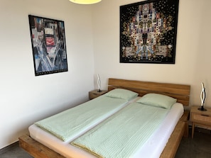Un dormitorio con una cama, dos mesitas de noche y dos lámparas de pared.