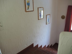 A staircase with a white wall and a red curtain. There are three framed pictures on the wall. - Casa Miriam by Interhome (Gordola)