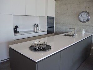 A modern kitchen with a central island, stainless steel appliances, and a wall-mounted clock. - Residenza Lotus by Interhome (Minusio)