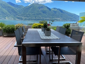 A deck with a table and chairs, overlooking a lake and mountains. - Residenza Lotus by Interhome (Minusio)