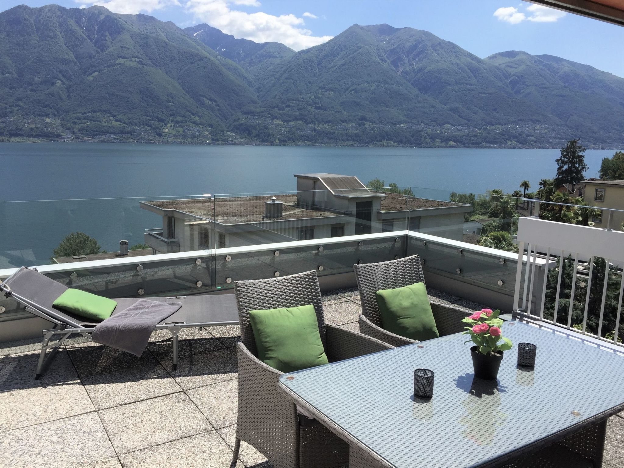 Une terrasse aménagée avec du mobilier d’extérieur, une table et une vue sur un lac et des montagnes.