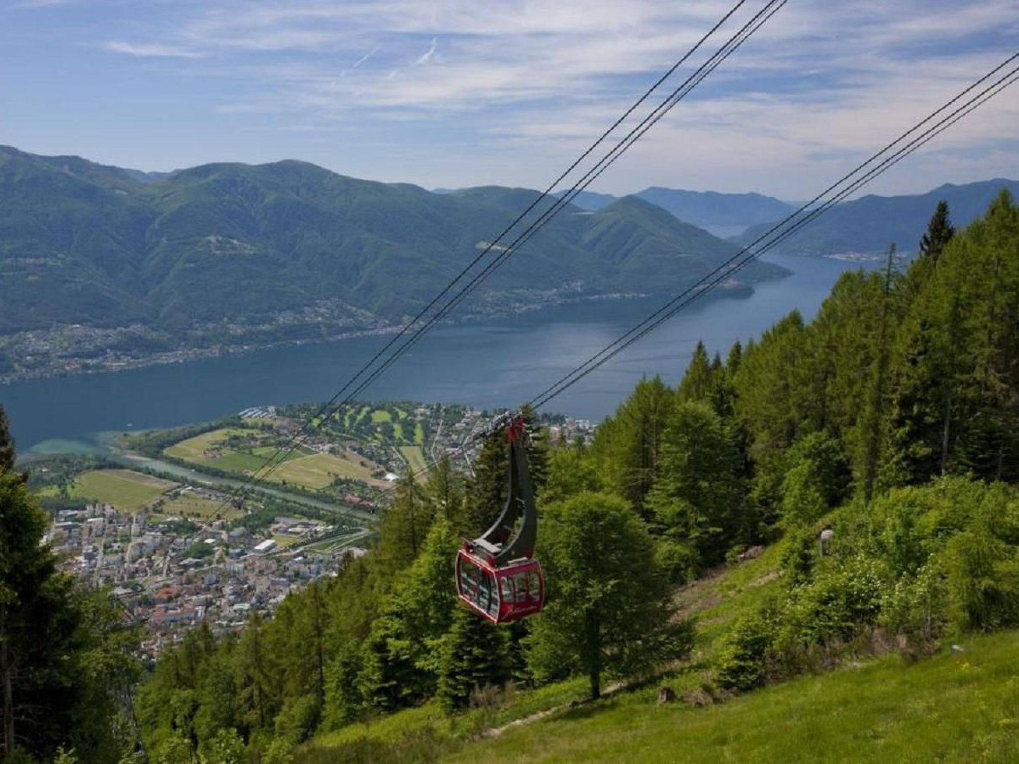 A cable car system with a mountainous landscape and a lake in the background.